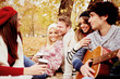 © chika_milan - Friends having a good time in park at autumn/ singing and playing guitar
