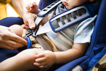 Father fastening seat belt for his son sitting in the car.