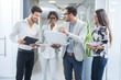 © Bojan - Group of four business people with laptop and documents having meeting in office hall.