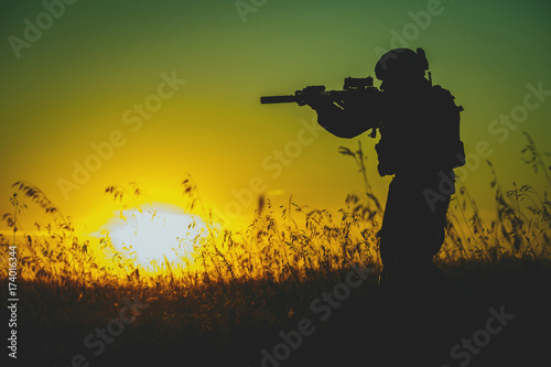 Plakat Sylwetka militarny żołnierz z broniami przy zmierzchem. strzał, trzymając pistolet, kolorowe niebo. koncepcja wojskowa.