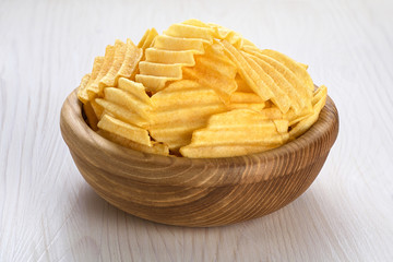 Wall Mural - Bowl with potato chips on a wooden background.