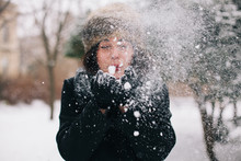 Woman Blowing Snow From Her Hands