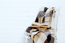 Wooden Chair With Plaid And Books On A Brick Wall Background
