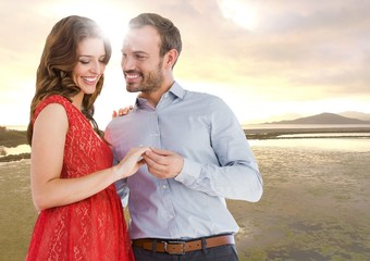 Canvas Print - Couple engaged against river in evening with flare