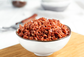 Wall Mural - Bowl with red rice on board, closeup