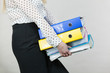 Woman holding heavy colorful binders with documents