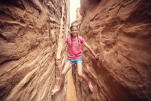 Happy Young Woman Climbing And Playing On The Narrow Slot Canyon Rock Walls While On Vacation In The Southwestern United States