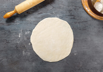 Poster - Raw pizza dough on dark surface in bakery, top view