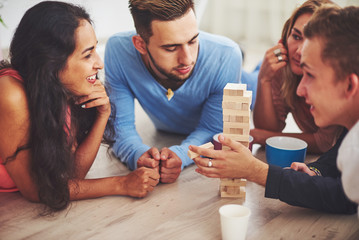 Wall Mural - Group of creative friends sitting at wooden table. People having fun while playing board game