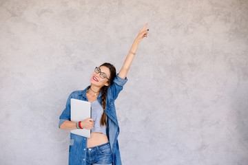 Wall Mural - Portrait of happy girl with laptop pointing with left arm up