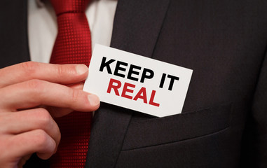 Poster - Businessman putting a card with text Keep It Real in the pocket