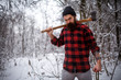 © endrews21 - A stylish woodcutter with a long beard cuts a tree in the snow in the woods