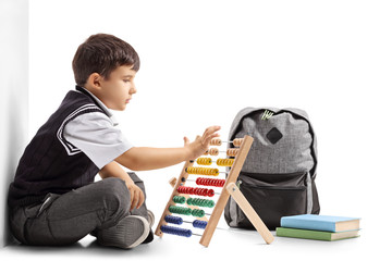 Poster - Schoolboy seated on the floor using an abacus