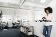 © Westend61 - Young woman holding VR glasses in office