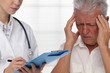 © dream@do - Female doctor Senior man suffering from a headache , migraine during medical exam.