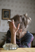 Senior Woman Sitting And Smoking In The Living Room