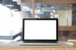 © bongkarn - Front view picture of workplace with blank screen laptop on wood table.