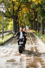 Vertical image of happy elegant couple rides on modern motorbike