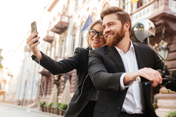 Smiling stylish couple satting on modern motorbike outdoors