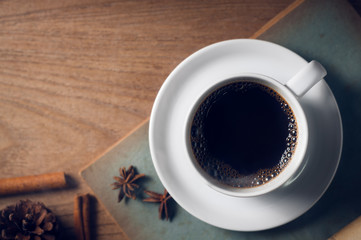 Coffee cup with old book on rustic wooden table, classic concept.