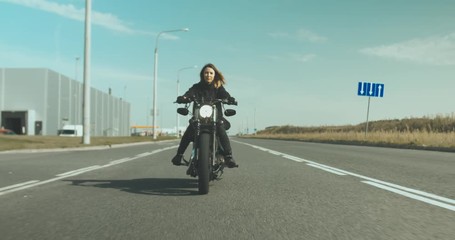 Wall Mural - TRACKING Beautiful Caucasian female biker riding her motorcycle near warehouse. 4K UHD RAW edited footage