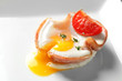 Tasty egg with tomato in ham on white plate, closeup