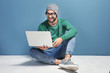 © Africa Studio - Young blogger with laptop sitting against color wall