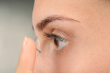 Fototapeta Panele - Young woman putting contact lens, closeup