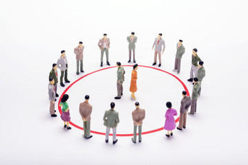 Wall Mural - Miniature business people standing in circle over backdrop or background.