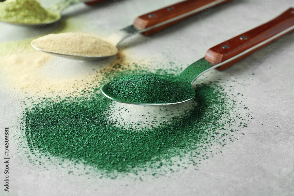 Different colorful superfood powders in spoons on table