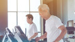 © glowonconcept - Healthy Asian senior couple exercise together in gym running treadmill
