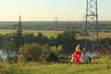 A photo of a traveler with a backpack, a girl sitting on the hill and thinking observing the sunset and the nature landscape on the hike.