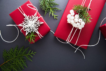 Wall Mural - christmas handmade gift boxes decorated with red paper, green branches and white snowflakes on dark 
