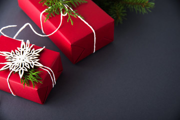 Wall Mural - christmas handmade gift boxes decorated with red paper and white snowflakes on dark grey background.