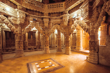 Poster - Columns with stone reliefs in Indian temple wall. Ancient architecture example with Jain motifs, Jaisalmer of India.