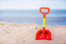 Red And Yellow Plastic Childrens Toy Shovel On A Beach