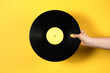 © Pixel Stories/Stocksy - Hand holding vinyl record over yellow background