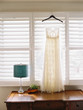 © wendy laurel/Stocksy - wedding dress hanging in window with blue lamp