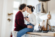 © minamoto images/Stocksy - A young couple hugging in a kitchen.