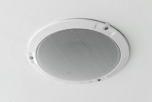 White round circle speaker and grille hanging on ceiling