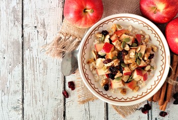 Wall Mural - autumn oatmeal with apples, cranberries, seed and nuts, overhead table scene on white wood