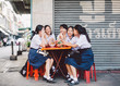 © Nabi Tang/Stocksy - Thai high school student sitting at street restaurant in Bangkok