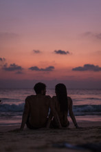 Romantic Couple On The Beach At Colorful Sunset In Background