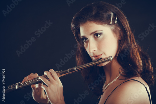 Plakat Kobieta bawić się poprzecznego flet na czerni.