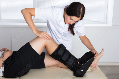 Fotomural Orthopedist Adjusting Walking Brace On Patient's Leg