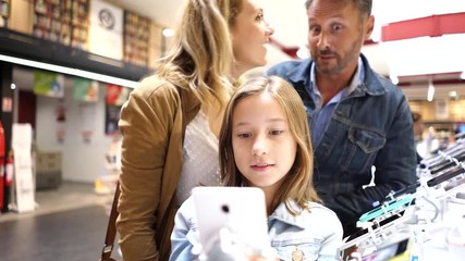 Wall Mural - Family at the multimedia store looking at smartphones