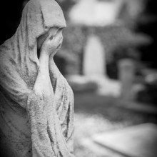 Statue Of A Sad Woman In Cemetery