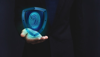 Network Security System Concept, Fingerprint inside a Shield Guard to Protected Identify of User or Personal Information, Present over Businessman Hand, Dark light and Modern Transparent style