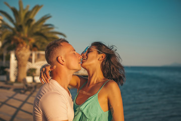 Wall Mural - Cute couple kissing in the park on a sunny day. Kissing couple. Happy day. Fashion photo. Sea background. Love story. Sensual. 