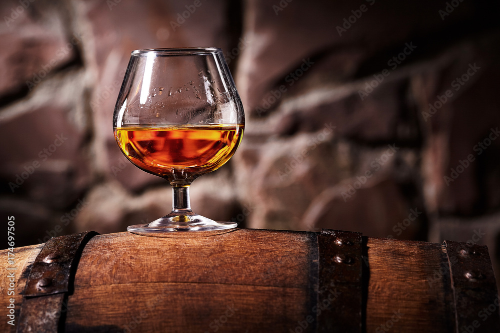 Glass of cognac on the old wooden barrel - obrazy, fototapety, plakaty 